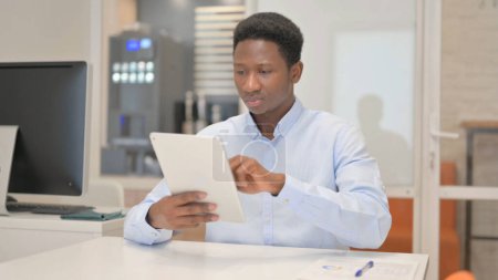 Téléchargez les photos : Homme d'affaires africain utilisant une tablette numérique au bureau - en image libre de droit