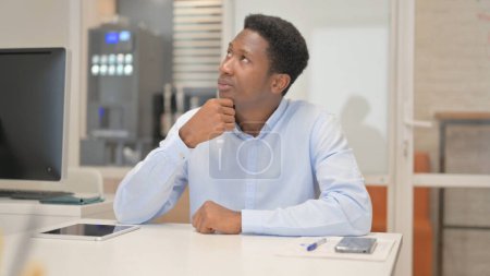 Téléchargez les photos : Homme d'affaires africain pensif assis au bureau - en image libre de droit