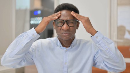 Téléchargez les photos : Portrait de l'homme d'affaires africain avec maux de tête au bureau - en image libre de droit