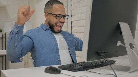 Foto de Empresario africano celebra éxito en computadora - Imagen libre de derechos