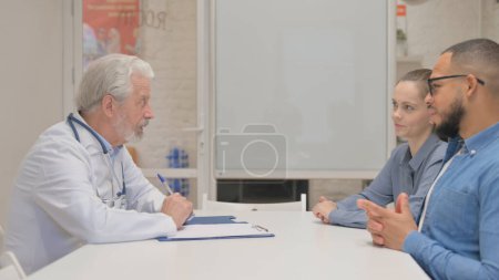 Foto de Médico principal discutiendo informe médico con pareja - Imagen libre de derechos
