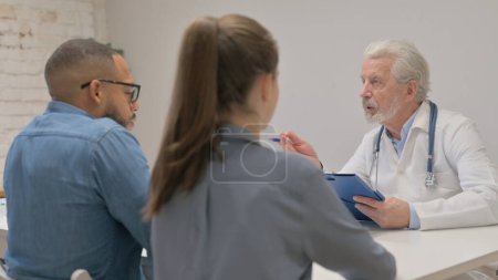 Téléchargez les photos : Gros plan du médecin principal parlant avec un couple - en image libre de droit