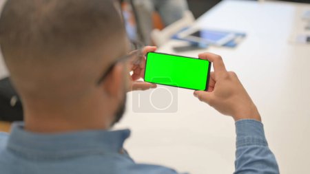 Téléchargez les photos : Homme hispanique tenant téléphone horizontal avec écran vert - en image libre de droit