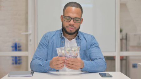 Téléchargez les photos : Jeune homme de race mixte comptant de l'argent - en image libre de droit