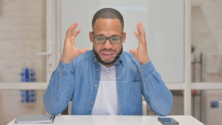 Téléchargez les photos : Homme de race mixte tendu ayant mal à la tête au bureau - en image libre de droit