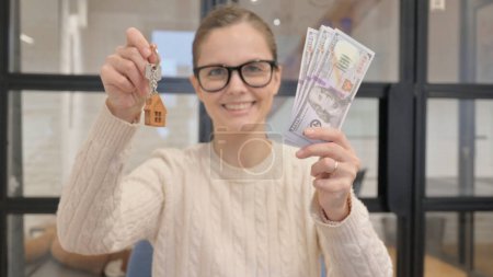Portrait de femme montrant les clés de la maison et de l'argent