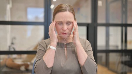 Téléchargez les photos : Portrait de femme d'affaires senior avec maux de tête au bureau - en image libre de droit