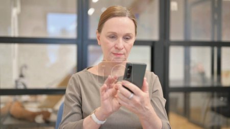 Téléchargez les photos : Portrait de femme d'affaires senior utilisant le téléphone au bureau - en image libre de droit