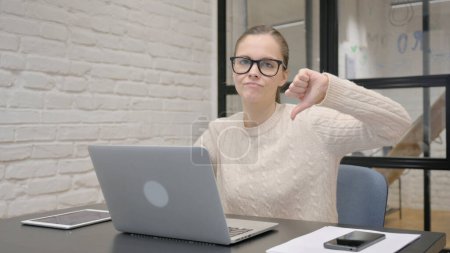 Thumbs Down by Creative Woman Using Laptop