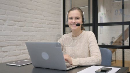 Foto de Mujer sonriente con auriculares en el centro de llamadas - Imagen libre de derechos