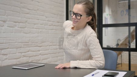Téléchargez les photos : Femme créative ayant mal au dos tout en étant assis au travail - en image libre de droit