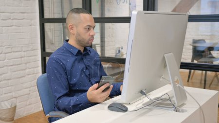 Téléchargez les photos : Homme d'affaires hispanique travaillant sur le bureau et utilisant un smartphone - en image libre de droit