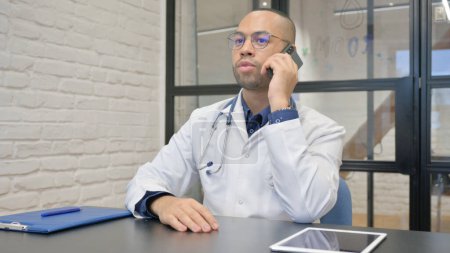 Foto de Médico hispano hablando por teléfono con paciente - Imagen libre de derechos
