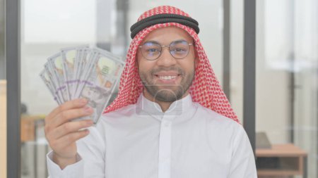 Téléchargez les photos : Portrait de jeune homme arabe montrant de l'argent - en image libre de droit
