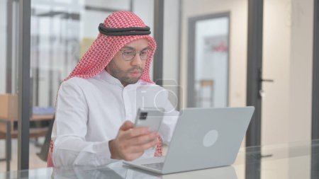 Téléchargez les photos : Jeune homme arabe utilisant des appareils numériques pour le travail - en image libre de droit