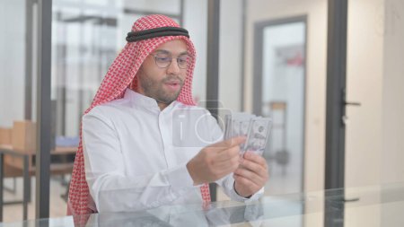 Téléchargez les photos : Jeune homme arabe Compter l'argent au travail - en image libre de droit