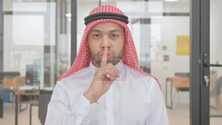 Téléchargez les photos : Portrait de jeune homme musulman avec doigt sur les lèvres, silence s'il vous plaît - en image libre de droit