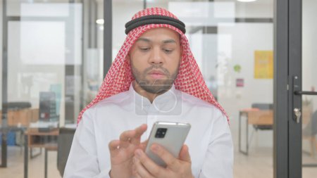 Téléchargez les photos : Portrait de jeune homme musulman utilisant le téléphone - en image libre de droit