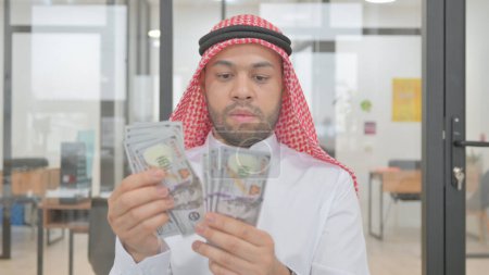 Téléchargez les photos : Portrait d'un jeune homme musulman comptant de l'argent - en image libre de droit