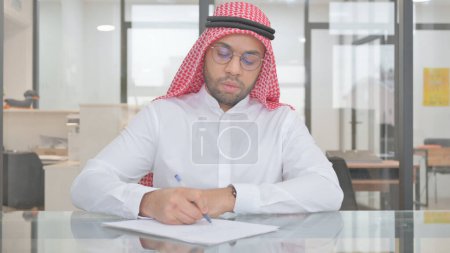 Foto de Joven musulmán escribiendo informe de negocios en el trabajo - Imagen libre de derechos