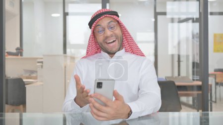 Téléchargez les photos : Jeune homme musulman célébrant le commerce en ligne par téléphone - en image libre de droit