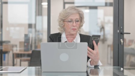 Photo for Senior Businesswoman Browsing Internet on Phone and Laptop - Royalty Free Image