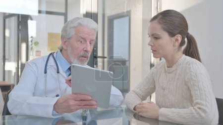 Foto de Paciente discutiendo problemas de salud con médico senior en tableta digital - Imagen libre de derechos