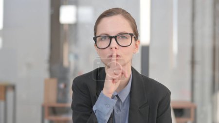 Portrait de jeune femme d'affaires avec doigt sur les lèvres, Silence Please