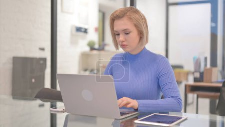 Téléchargez les photos : Jeune femme travaillant sur ordinateur portable au bureau - en image libre de droit