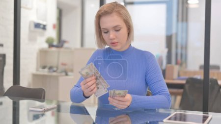 Junge Frau beim Geldzählen am Arbeitsplatz