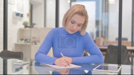 Téléchargez les photos : Jeune femme écrivant une lettre au bureau - en image libre de droit