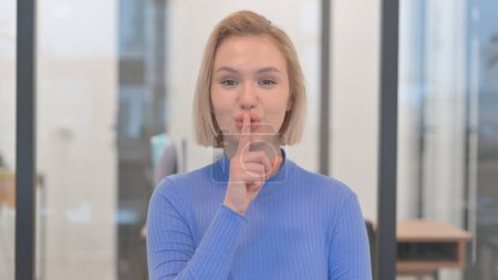 Porträt einer jungen Frau mit dem Finger auf den Lippen, bitte schweigen