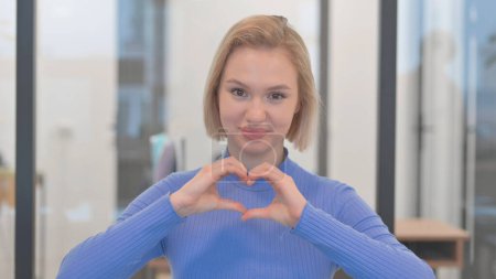 Téléchargez les photos : Portrait de jeune femme exprimant l'amour avec signe de coeur fait main - en image libre de droit