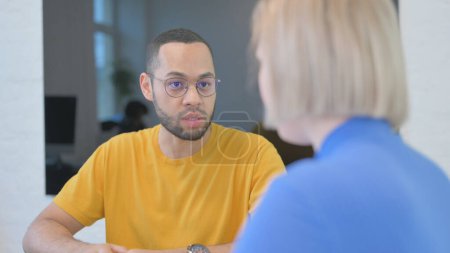 Foto de Hombre de raza mixta hablando con una joven en la oficina - Imagen libre de derechos