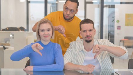 Photo for Portrait of Mixed Race Teammates in Office with Thumbs Down - Royalty Free Image
