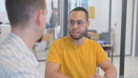 Téléchargez les photos : Gros plan d'un homme de race mixte parlant avec un coéquipier créatif - en image libre de droit