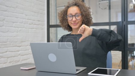 Photo for Hispanic Woman Showing Thumbs Down while Working on Laptop - Royalty Free Image