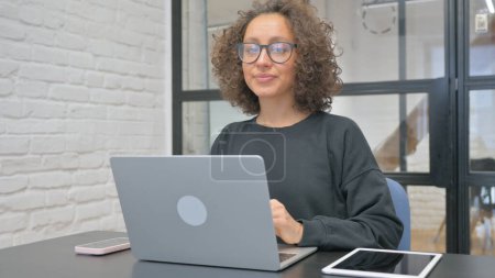 Téléchargez les photos : Femme hispanique avec geste d'approbation tout en travaillant sur ordinateur portable - en image libre de droit