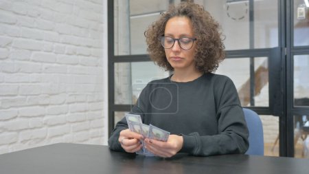 La femme hispanique compte l'argent au bureau
