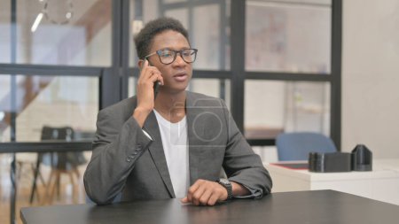Téléchargez les photos : Afro-Américain Parler au téléphone au bureau - en image libre de droit