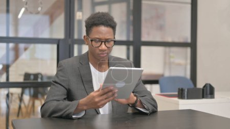 Téléchargez les photos : Afro-Américain utilisant la tablette numérique dans le bureau - en image libre de droit