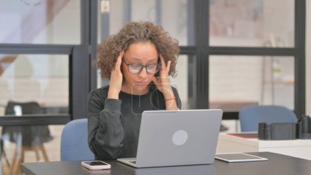 Téléchargez les photos : Femme de race mixte ayant mal à la tête au travail - en image libre de droit
