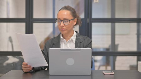 Téléchargez les photos : Femme d'affaires métisse travaillant sur des documents au bureau - en image libre de droit