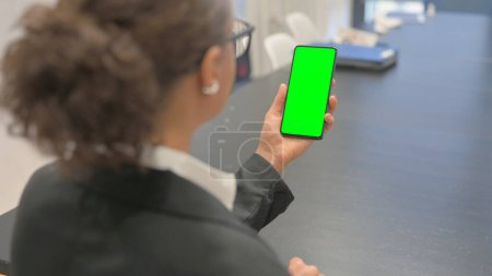 Téléchargez les photos : Vue arrière de la femme d'affaires avec Smartphone à écran vert - en image libre de droit