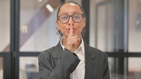 Foto de Retrato de una mujer de negocios hispana pidiendo silencio, con el dedo en los labios - Imagen libre de derechos