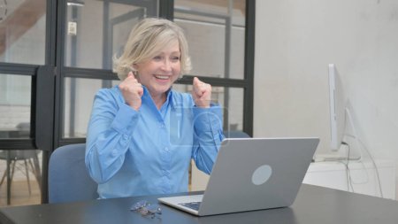 Foto de Anciana mayor emocionada por el comercio en línea en el ordenador portátil en la oficina - Imagen libre de derechos