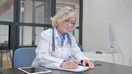 Foto de Doctora Senior escribiendo informe médico en el hospital - Imagen libre de derechos