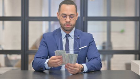 Homme d'affaires de race mixte comptant l'argent, billets
