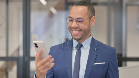 Foto de Retrato del hombre de negocios de raza mixta celebrando el éxito en el teléfono - Imagen libre de derechos