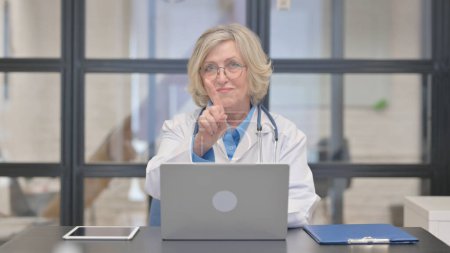 Foto de Restringir a la vieja doctora mirando la cámara mientras trabaja en el ordenador portátil - Imagen libre de derechos